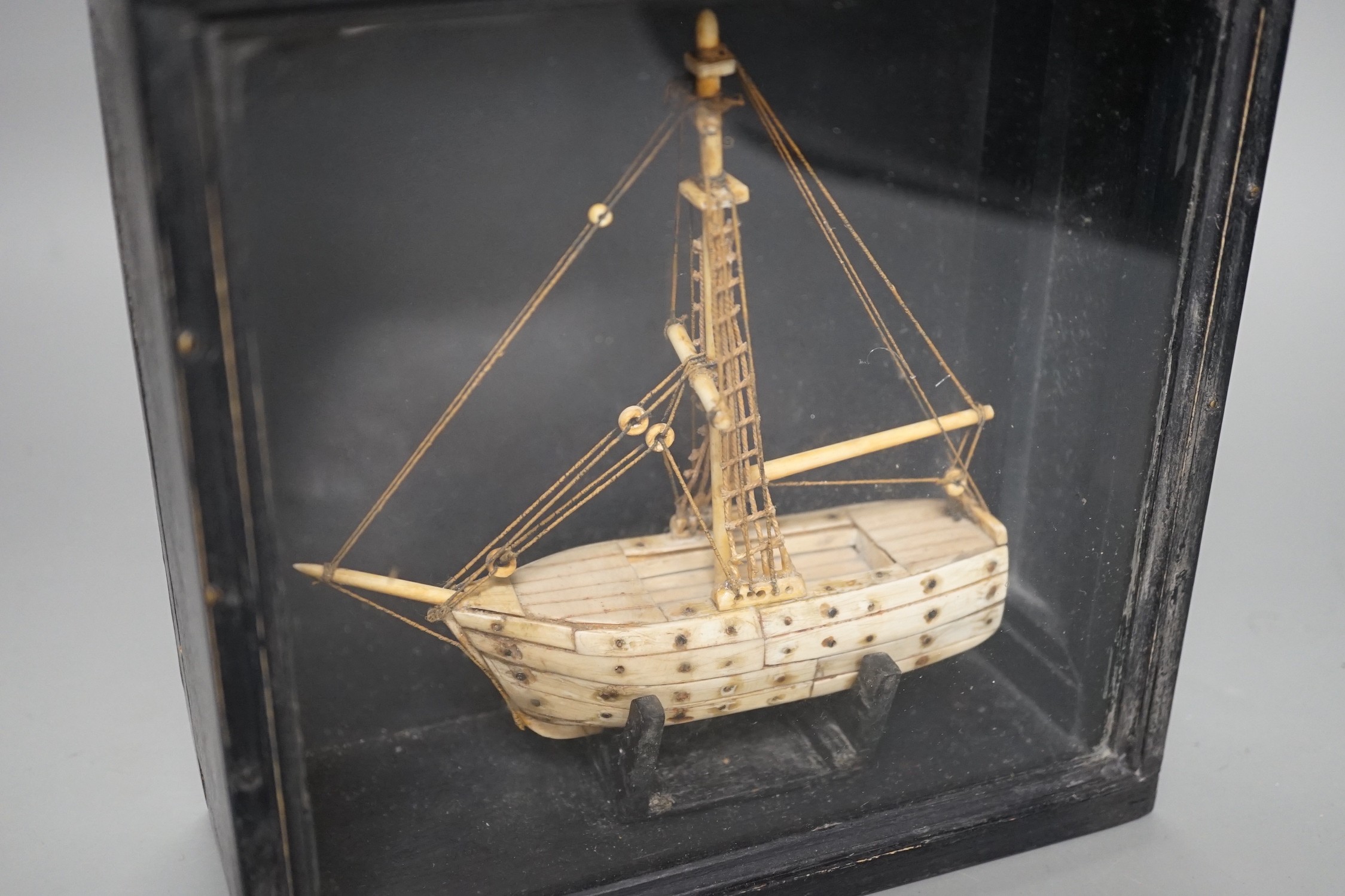 A cased bone Napoleonic style, carved prisoner-of-war ship, 18cms wide x 18.5cms high